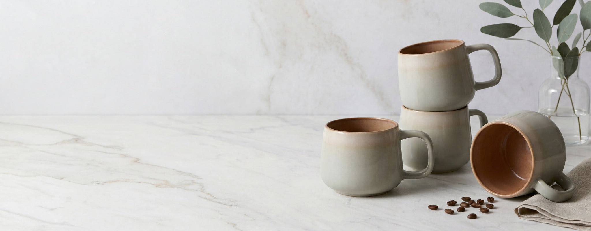 Sage ceramic coffee mugs on white marble with eucalyptus — AVA NORD
